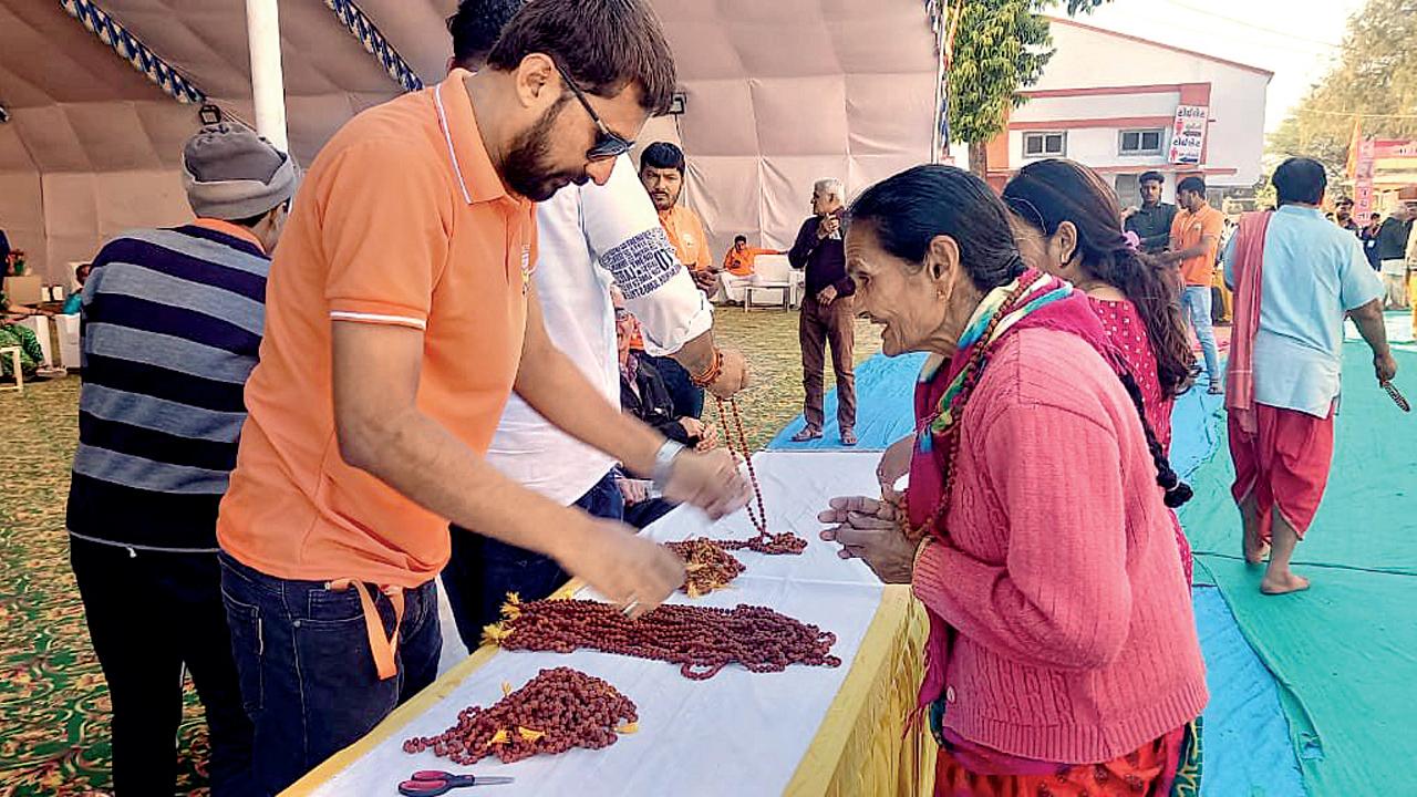 મહેસાણા જિલ્લાના સાલડી ગામે પિંપળેશ્વર મહાદેવના પુનઃ પ્રાણપ્રતિષ્ઠા મહોત્સવમાં દર્શનાર્થીઓને પ્રસાદી તરીકે રુદ્રાક્ષની માળાઓ આપી રહેલો અમેરિકાથી આવેલો ભાવિક